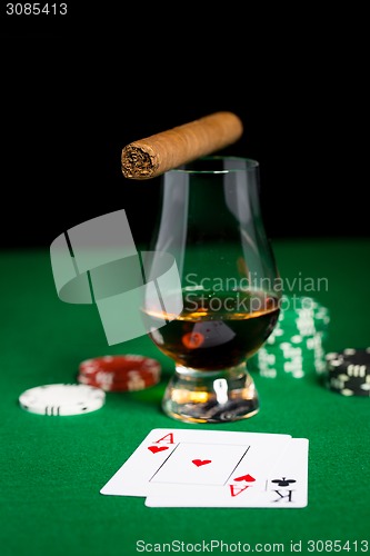 Image of close up of chips, cards whisky and cigar on table