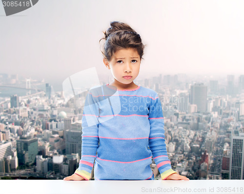 Image of sad little girl over city background