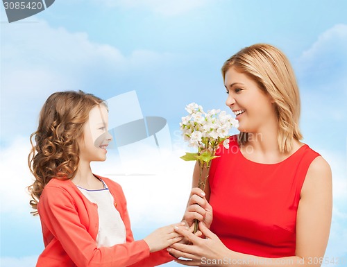 Image of happy little daughter giving flowers to her mother