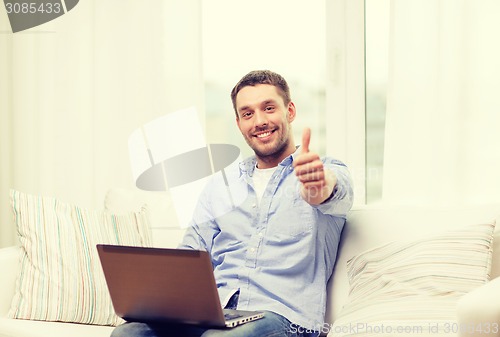 Image of smiling man working with laptop at home