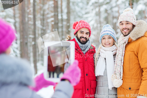 Image of smiling friends with tablet pc in winter forest