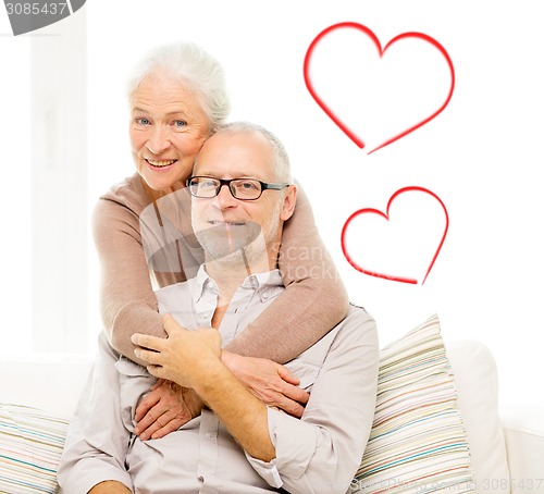 Image of happy senior couple hugging on sofa at home