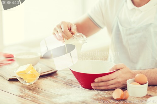 Image of close up of male hand pouring milk in bowl