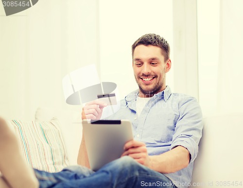 Image of smiling man working with tablet pc at home