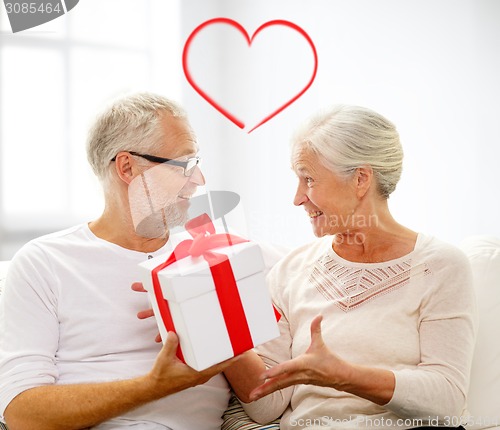 Image of happy senior couple with gift box at home