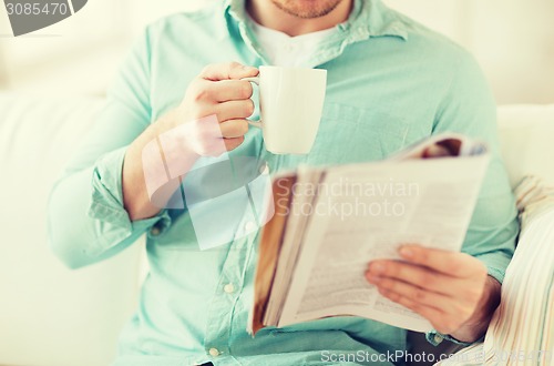 Image of close up of man with magazine drinking from cup