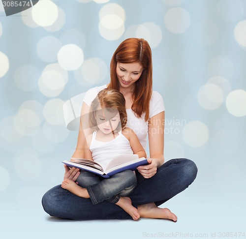 Image of happy mother with adorable little girl and book