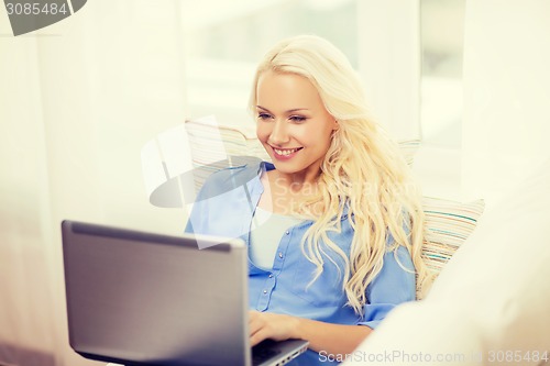 Image of smiling woman with laptop computer at home