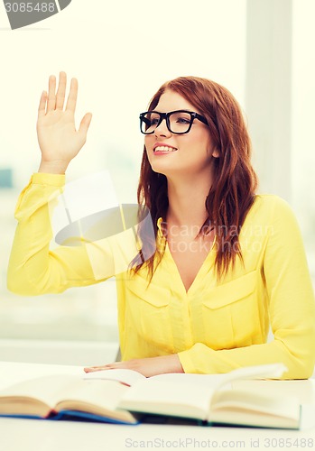 Image of smiling student girl with books and raised hand