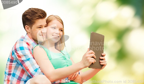 Image of couple with tablet pc taking selfie over green