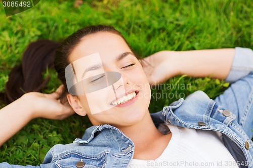 Image of smiling young girl with closed eyes lying on grass