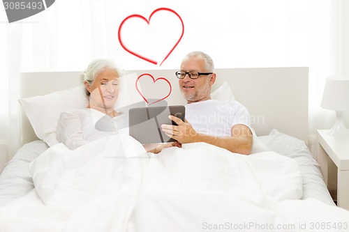 Image of happy senior couple with tablet pc at home