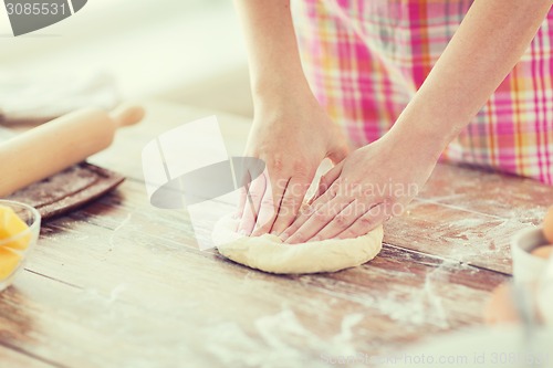 Image of close up of female hands kneading dough at home