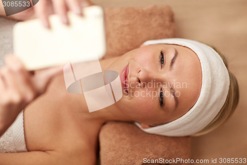 Image of close up of smiling woman with smartphone in spa