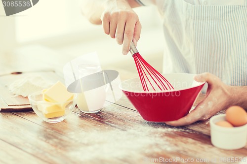 Image of close up of male hand whisking something in a bowl