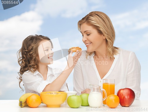 Image of happy mother and daughter eating breakfast