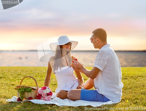 Image of smiling couple with small red gift box on picnic