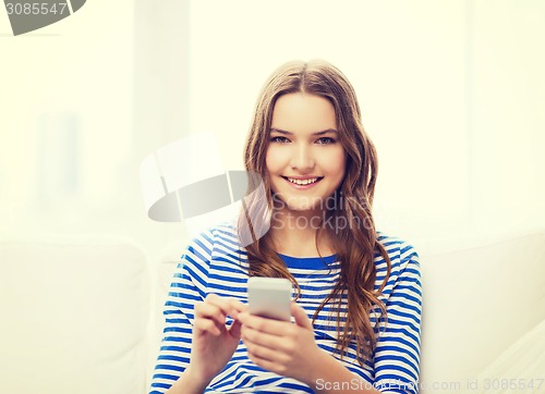 Image of smiling teenage girl with smartphone at home