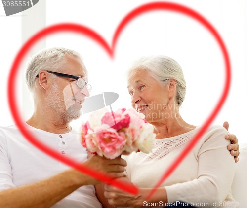 Image of happy senior couple with bunch of flowers at home