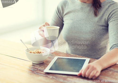 Image of woman drinking coffee and using tablet pc