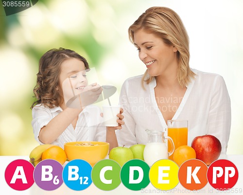 Image of happy mother and daughter eating breakfast