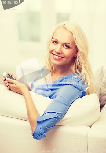 Image of smiling woman with smartphone at home