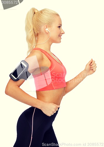 Image of sporty woman running with smartphone and earphones