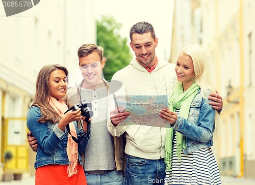 Image of group of smiling friends with map and photocamera