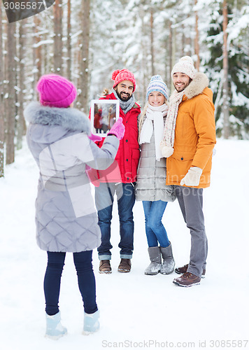 Image of smiling friends with tablet pc in winter forest