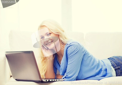 Image of smiling woman with smartphone and laptop at home