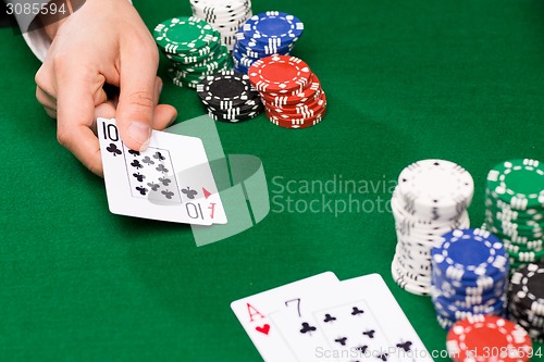 Image of poker player with cards and chips at casino