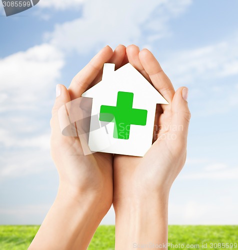 Image of hands holding paper house with green cross