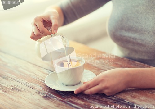 Image of close up of female pouring milk into coffee