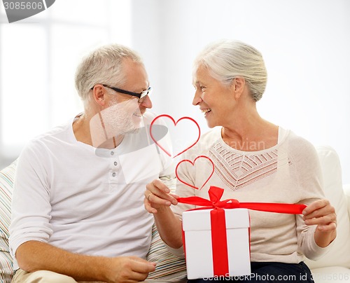 Image of happy senior couple with gift box at home