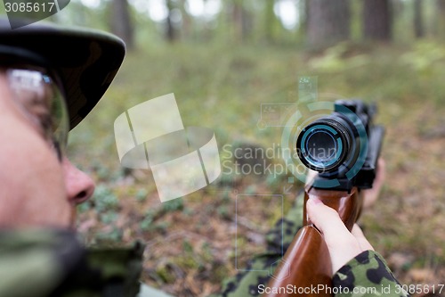 Image of close up of soldier or sniper with gun in forest