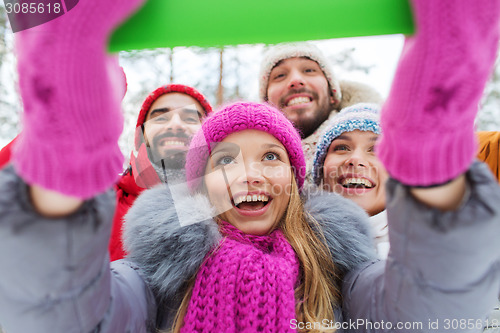Image of smiling friends with tablet pc in winter forest
