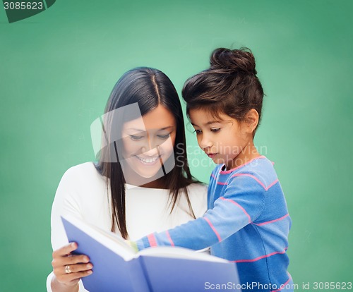 Image of happy teacher and little schoolgirl reading book