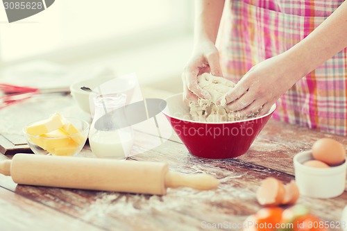 Image of close up of female hands kneading dough at home