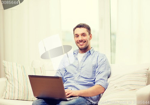 Image of smiling man working with laptop at home