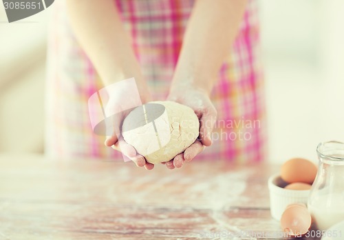 Image of close up of female hands holding bread dough