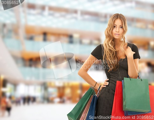 Image of young happy woman with shopping bags in mall