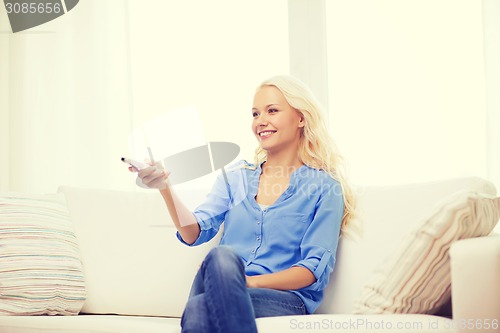 Image of smiling young girl with tv remote control at home