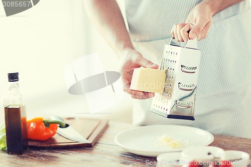 Image of close up of male hands grating cheese