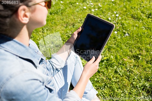 Image of close up of girl with tablet pc sitting on grass