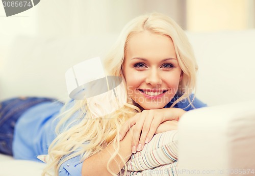 Image of smiling young woman lying on sofa at home