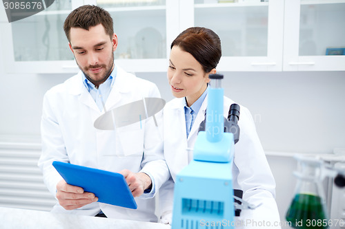 Image of scientists with tablet pc and microscope in lab