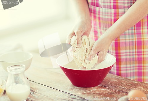 Image of close up of female hands kneading dough at home