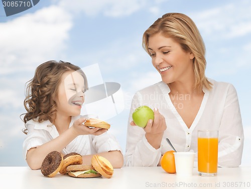 Image of happy mother and daughter eating breakfast