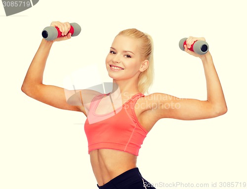 Image of smiling beautiful sporty woman with dumbbells