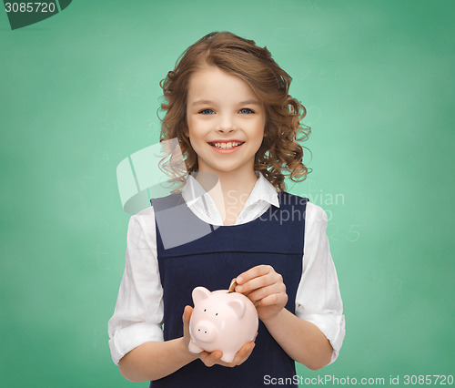 Image of smiling girl putting coin into piggy bank